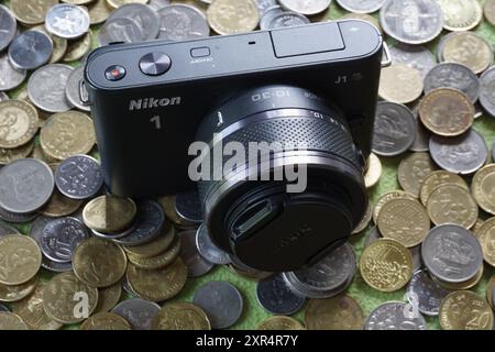 Terengganu, Malaysia - 24. August 2024: Nahaufnahme der schwarzen nikon 1 j1 spiegellosen Kamera auf verstreuten malaysischen Münzen Stockfoto