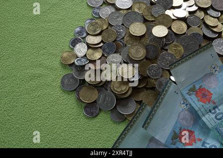 Terengganu, Malaysia - 24. August 2024 : Nahaufnahme der verstreuten malaysischen Münzen und 50 Ringgit malaysisches Geld auf grünem Hintergrund Stockfoto