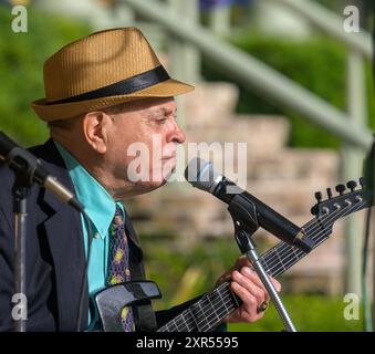 NEW ORLEANS, LA, USA – 10. FEBRUAR 2024: Deacon John Moore und der Hals und der Kopfstock seiner Parker-Gitarre, während er sich in das Mikrofon lehnt Stockfoto