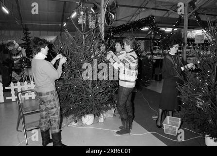 Dekoration eines Weihnachtsbaums durch die Bürgermeisterin der Region und Porträt von Mr. Kooy aus dem Gartenzentrum, Weihnachts- und Weihnachtsbäume, Gärten und Parks, 09-12-1985, Whizgle Dutch News: Historische Bilder zugeschnitten auf die Zukunft. Erkunden Sie die Vergangenheit der Niederlande mit modernen Perspektiven durch Bilder von niederländischen Agenturen. Verbinden der Ereignisse von gestern mit den Erkenntnissen von morgen. Begeben Sie sich auf eine zeitlose Reise mit Geschichten, die unsere Zukunft prägen. Stockfoto