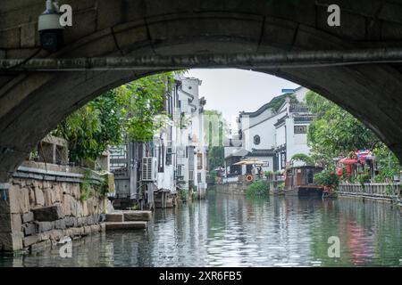 Suzhou, China - 11. Juni 2024 : Blick von einer bogenförmigen Steinbrücke über einen Kanal in Suzhou, China. Stockfoto