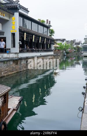 Suzhou, China - 11. Juni 2024 : Ein ruhiger Kanal spiegelt die traditionelle Architektur von Suzhou, China, wider, mit Gebäuden am Ufer. Stockfoto