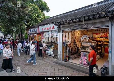 Suzhou, China - 11. Juni 2024 : Eine belebte Straße in Suzhou, China, mit einer Vielzahl von Geschäften und Menschen, die zu Fuß vorbeilaufen. Stockfoto