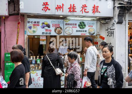 Suzhou, China - 11. Juni 2024 : die Leute laufen an einem Straßenverkäufer in Suzhou, China, auf der Pingjiang Road vorbei, schauen sich die Speisekarte an und entscheiden, was sie essen sollen Stockfoto