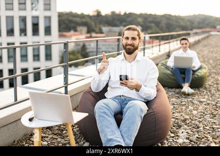 Mitarbeiter im Außenbereich genießen Fernarbeiten auf der Dachterrasse Stockfoto