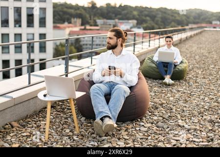 Geschäftsleute, die per Fernzugriff auf dem Dach mit Laptops arbeiten Stockfoto