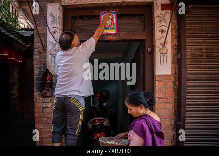 Bhaktapur, Bagmati, Nepal. August 2024. Ein Mann verehrt Schlangengottheit (Schlange) an der Haupttür des Hauses mit einer Baumwolllampe nach Opfergaben während des Nag Panchami Festivals. Die Leute an diesem Tag kleben das Poster der Schlangengottheit (Schlange) auf die Haupttür des Hauses, reinigen den nächstgelegenen Teich und verehren Schlangengötter, auch Nagas genannt während Nag Panchami. (Kreditbild: © Amit Machamasi/ZUMA Press Wire) NUR REDAKTIONELLE VERWENDUNG! Nicht für kommerzielle ZWECKE! Quelle: ZUMA Press, Inc./Alamy Live News Stockfoto