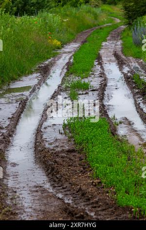 Abgebrochene Feldstraße in den Frühlingsbergen mit vielen schlammigen Pfützen nach dem Regen. Stockfoto