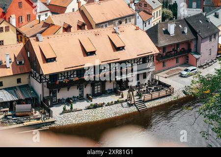 Ein charmantes Restaurant mit Sitzgelegenheiten im Freien säumt die Ufer eines Flusses, umgeben von lebhaften Häusern in verschiedenen Farbtönen. Die Einstellung erfasst ein su Stockfoto