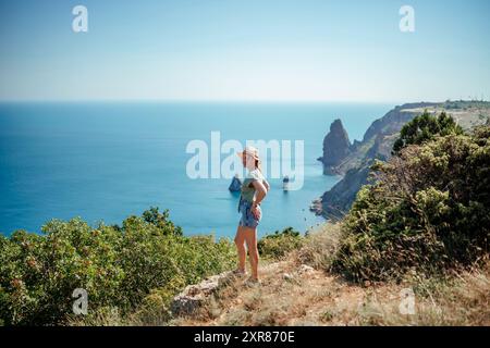 Eine Frau steht auf einem Hügel mit Blick auf das Meer Stockfoto