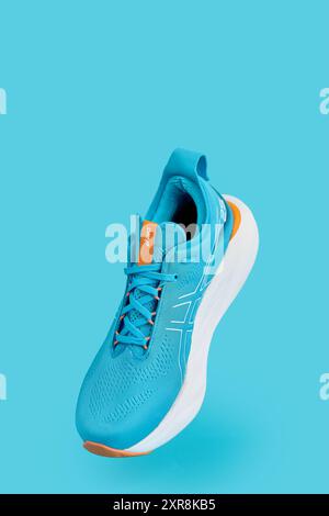 Einzelner blauer Asics Gel-Nimbus 25 Sport-Sneaker auf blauem Hintergrund. Elegantes, modisches Minimalismus-Konzept. Flugschuhe Stockfoto