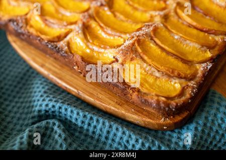 Ein Dessert aus geschnittenen Pfirsichen ist auf einem hölzernen Schneidebrett. Das Dessert ist mit Zucker bedeckt und sieht köstlich aus. Stockfoto