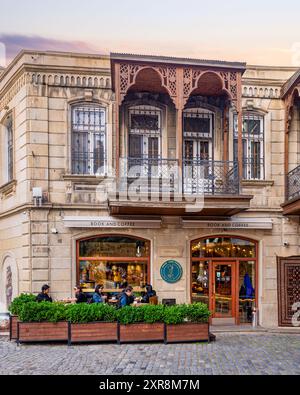 Baku, Aserbaidschan - 4. Mai 2024: Besucher genießen Getränke und Lesen, während sie sich vor Sonnenuntergang in einem gemütlichen Buch- und Kaffeehaus in der historischen Altstadt oder Icherisheher entspannen Stockfoto