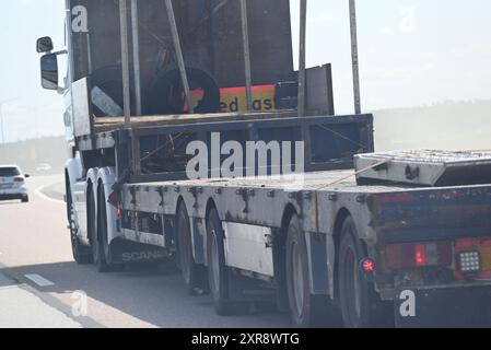 Lastkraftwagen, gerader Lkw mit Flachdeck-Anhänger ohne Last, der auf staubigen Straßen fährt. Stockfoto