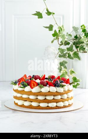 Ein ganzer Kuchen, dekoriert mit frischen Erdbeeren auf weißem Marmor Stockfoto