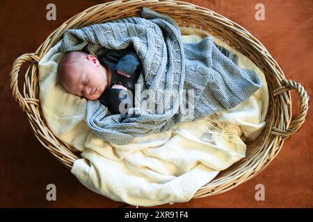 Neugeborenes Baby im grauen Outfit, das in einem Korbkorb mit einem k schläft Stockfoto