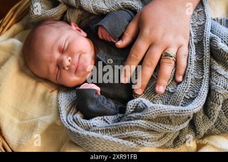 Neugeborenes Baby im grauen Outfit, das mit einer Strickdecke schläft, Par Stockfoto