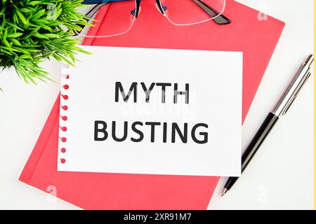 Mythenbrecher-Wort-Konzept in einem weißen Notizbuch auf einem roten Geschäftsbuch Stockfoto