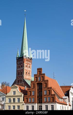 Turm der Peterskirche in Lübeck, Deutschland, erhebt sich neben den Giebeln alter Häuser Stockfoto