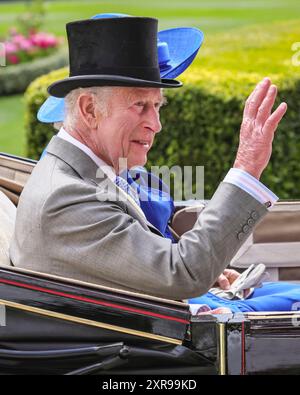 König Karl III., in einem Tophut, lächelt und winkt von der Kutsche während der königlichen Prozession in Royal Ascot, England, Großbritannien Stockfoto