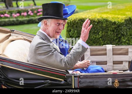 König Karl III., in einem Tophut, lächelt und winkt von der Kutsche während der königlichen Prozession in Royal Ascot, England, Großbritannien Stockfoto