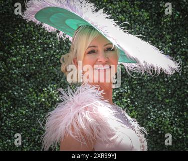 Elegantes weibliches Rennpferd im Kleid mit Straußenfedern und Hut bei Royal Ascot Horse Racing, Berkshire, Großbritannien Stockfoto