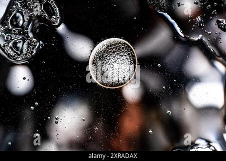 Detaillierte Nahaufnahme von Luftblasen, die auf einer dunklen Oberfläche schweben, wodurch eine abstrakte und geheimnisvolle Komposition entsteht. Vorlage für Hintergründe, wissenschaftliche Darstellungen Stockfoto