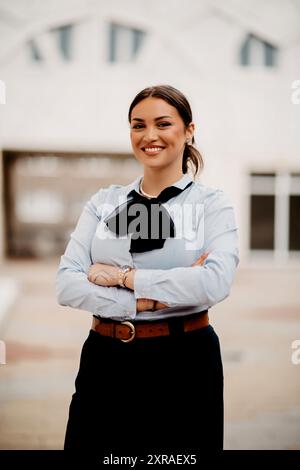 Die lächelnde Latina-Geschäftsfrau schreitet selbstbewusst durch die Straßen der Stadt. Stockfoto