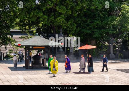 Narita, Japan - 23. Juli 2024: Priester gehen an einem sonnigen Sommertag in Richtung der Haupthalle des Naritasan Shinsho-JI-Tempels in der Nähe von Tokio Stockfoto