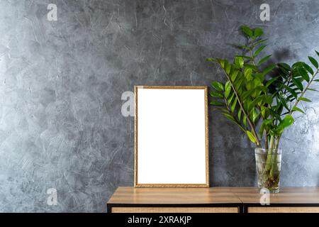 Stillleben beim Frühstück. Leeres Bilderrahmen-Modell auf Holztisch, Tisch. Vase mit Olivenzweigen. Eleganter Arbeitsbereich, Home Office-Konzept. Skandina Stockfoto