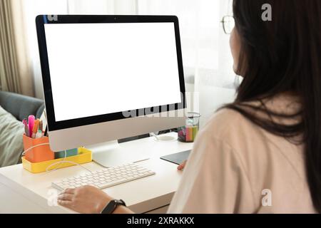 Nahaufnahme Porträt einer schönen Geschäftsfrau im Anzug, die am Computer mit Dokumenten im hellen Büro arbeitet und auf den Monitor blickt. Kopierbereich für Adver Stockfoto
