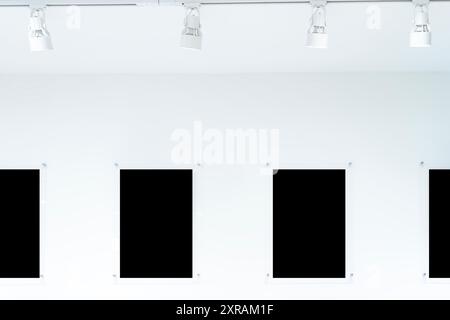 Eine Reihe schwarzer Rahmen hängt an einer weißen Wand und beschneidet den Pfad. Sie bestehen alle aus verschiedenen Materialien. Die Rahmen sorgen für ein interessantes und optisches Erscheinungsbild des Stockfoto