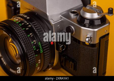 Detailansicht des Objektivs einer Vintage-Kamera mit gelbem Hintergrund. Betont das komplizierte Design und die Nostalgie. Stockfoto