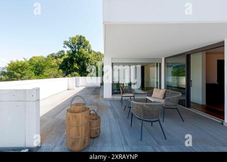 Außenbalkon der Villa modena mit einem kleinen Wohnzimmer, bestehend aus einem Sofa und zwei Sesseln. Im Hintergrund grüne Bäume. Niemand drinnen Stockfoto