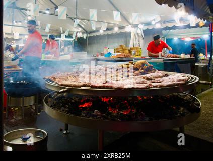 Köche in der Cocina de Galicia unter einem Festzelt mit einem großen Feuer und Fleischkochen während der Semana Grande öffentlichen Veranstaltung Santander Cantabria Spanien Stockfoto