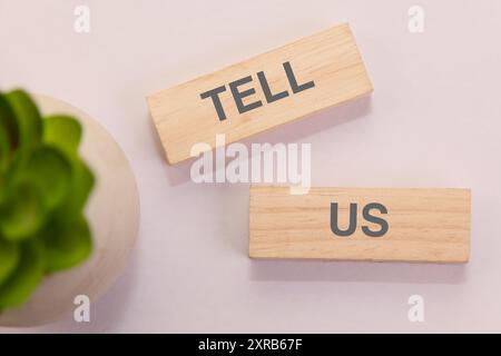 Holzblöcke, die „Tell US“ mit einem Sukkulenten schreiben, perfekt für Feedback, Rezensionen oder Kommunikationskonzepte. Stockfoto