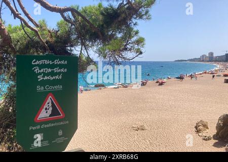 29. Juli 2024, Spanien, Platja D'Aro: Ein Schild an Platja Gran, dem „großen Strand“, weist auf Steinschlag hin. Strände verschwinden auf der ganzen Welt. In Spanien ist das Phänomen jedoch besonders akut. Die Zeitung "La Vanguardia" schrieb kürzlich, dass der "große Strand", der heute durchschnittlich gut 50 Meter breit ist, in den 1980er Jahren dreimal so groß war Umweltschützer gehen an die Barrikaden, und die ersten Küstenstädte ergreifen drastische Maßnahmen. Foto: Emilio Rappold/dpa Stockfoto