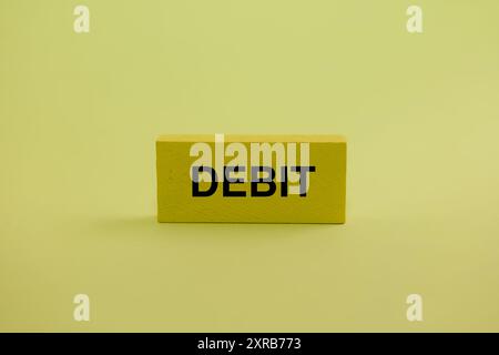 Ein einfacher gelber Holzblock mit „DEBIT“ in fetten schwarzen Buchstaben. Perfekt für Finanz- und Buchhaltungsgrafiken. Stockfoto