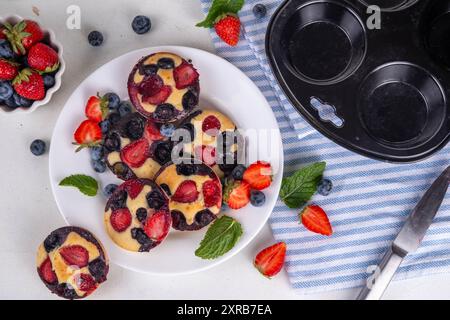 Portionierte gemischte Beerenblätter Pan Baked Pancakes, einfaches Rezept in Muffindosen. Mit frischer Heidelbeere und Erdbeere, Kopierraum Stockfoto