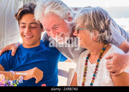 Glückliche gemischte Alters- und Generationen kaukasische Familie mit jungen Erwachsenen und Senioren zusammen genießen und Spaß haben. Fröhliche Großväter genießen Partyurlaub. Eine Gruppe von Menschen lächelt und hat Freizeitaktivitäten Stockfoto