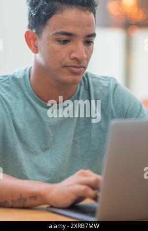 Lächelnder junger Mann Freiberufler mit Laptop Online-Studium von zu Hause aus arbeiten, glücklich casual Hipster Kerl tippen auf pc Notebook Surfen Internet Blick auf Bildschirm genießen entfernten Job sitzen am Tisch Stockfoto