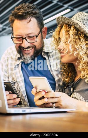 Reisen und moderne alternative Arbeitsplätze mit Laptop. Pärchen benutzte am Flughafen Telefone und Computer und wartete auf die Abreise. Mann und Frau lächeln und genießen die Online-Verbindung. Reisenden und Technologie Leben Stockfoto