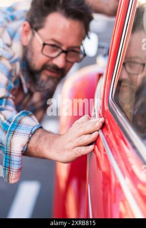 Erwachsener bärtiger Hipster-Mann überprüft die Politur seiner schönen Auto im Freien - Menschen und Autotransport Liebe und Pflege Konzept – der Fahrer sieht sich das Äußere seines Autos an Stockfoto