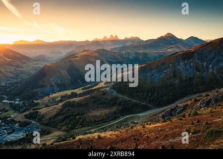 Blick aus der Vogelperspektive auf den Sonnenaufgang über dem Arves-Massiv zwischen den französischen Alpen mit einer Skistadt im Tal im Herbst am Lac Guichard, Frankreich Stockfoto