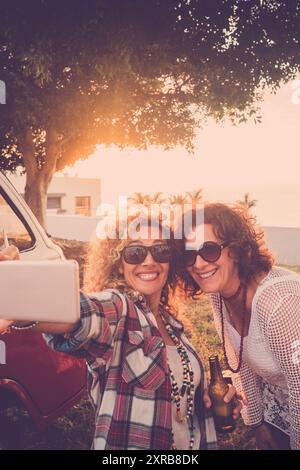 Paar weibliche Freunde genießen und Spaß haben zusammen nehmen Selfie im Freien - vintage roten Van und Sonnenlicht in Hintergrund - alternative Menschen Frauen in Freundschaft lächeln an der park in Freizeitaktivitäten Stockfoto