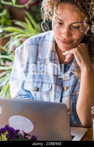 Reife Frau arbeitet am Computer, sitzt auf dem Desktop des Home Office und blickt lächelnd auf den Laptop - kostenlose moderne freiberufliche Mitarbeiter - Smart Working Online Internet Job Lifestyle - Kommunikation Stockfoto