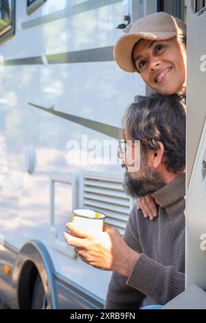 Junges Paar Touristen mit Wohnmobil vor der Tür sitzen und die Natur im Freien genießen. Reiseziel für Menschen und Berge. Mann und Frau leben zusammen im Van-Leben Stockfoto