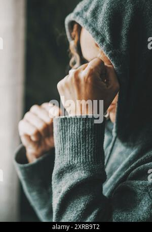 Frau, die einen schlechten Tag mit Verzweiflung und Frustration hat. Seitenansicht einer einsamen Frau zu Hause mit Stress und Problemen. Ende der Beziehung für Personen. Eine übermäßig besorgte Dame am Fenster Stockfoto