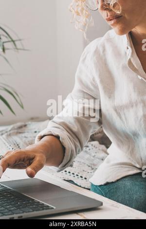 Designer bei der Arbeit im Heimbüro mit einem Laptop. Frau mit Laptop und Wireless-Technologie. Moderne Menschen mit Computer und Papier arbeiten online. Indoor-Freizeitangebote für Leute und Geschäftsanschluß Stockfoto