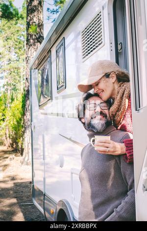 Glückliche Menschen im Reisestil sitzen vor der Tür eines Wohnmobils, der im Naturwaldpark parkt. Genießen Sie Vanlife-Paar. Mietfahrzeug für Urlaub und abseits des Stromnetzes unabhängiges Haus Wohnmobil Stockfoto